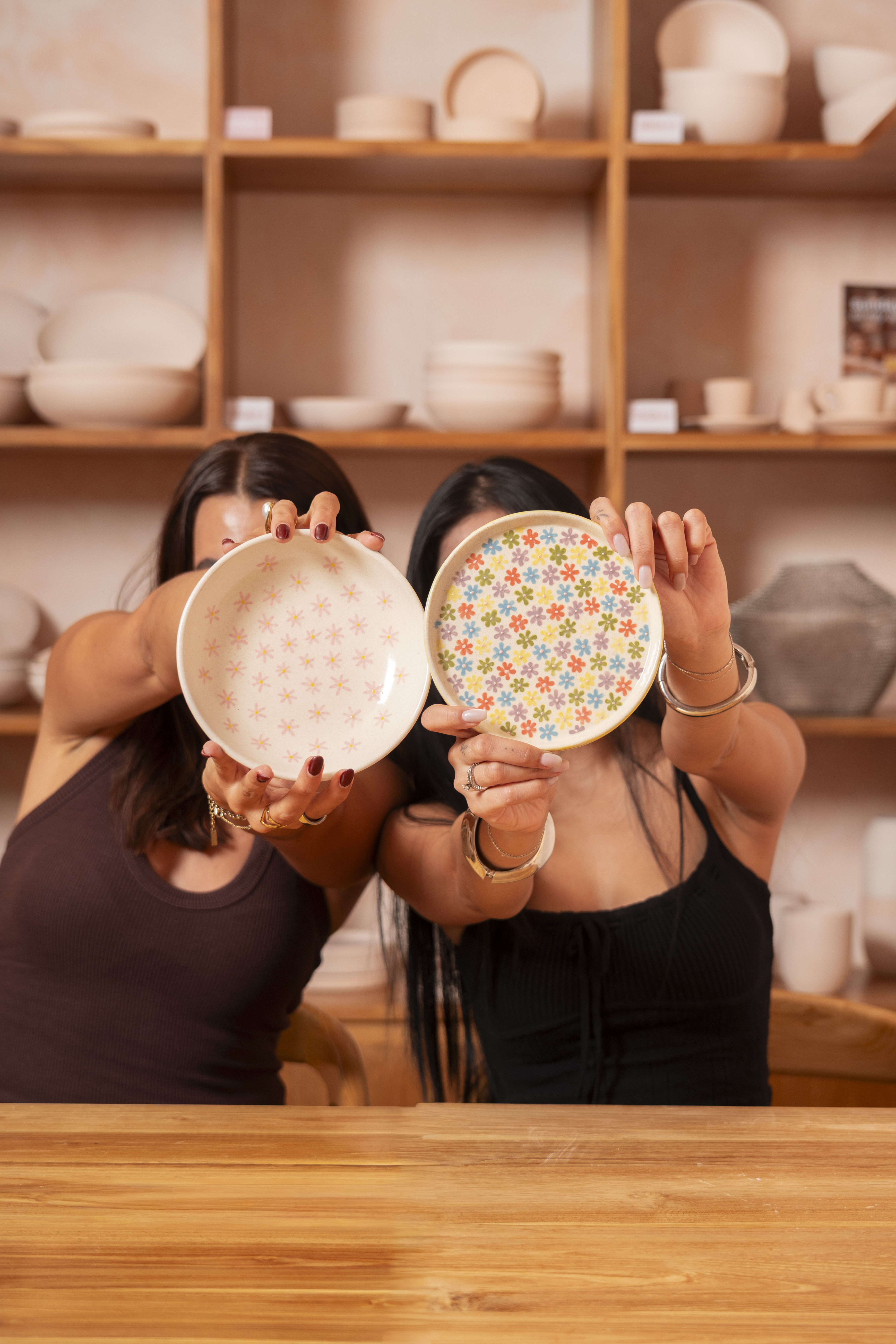 Guests holding up hand-painted ceramic plates at Klay Bar in Canggu, showcasing colourful patterns created during a relaxed ceramic painting session.